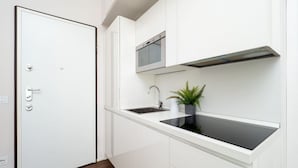 A modern kitchen with white cabinetry, a built-in microwave, and a black induction cooktop. - The Best Rent - Bright one-bedroom apartment in Milan (Milano)