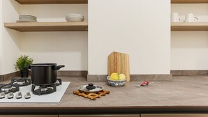 A kitchen with a stove, pots, a bowl of fruit, and a cutting board. - The Best Rent - Flat with 1 bedroom in Moscova area (Milano)
