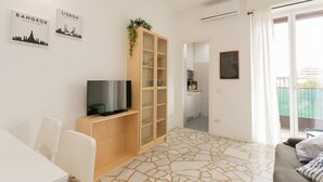 A modern living room with a TV, a wooden cabinet, and a balcony with a view. - The Best Rent - Two bedrooms apartment near metro station Maciachini (Milano)