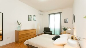 A bedroom with a bed, dresser, chair, and a bedside table with a lamp. - The Best Rent - Two bedrooms apartment near metro station Maciachini (Milano)