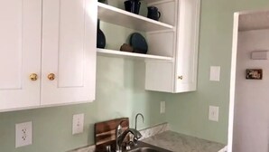 Een keuken met witte kasten, een marmeren aanrechtblad en een inbouwkastje met decoratieve objecten.