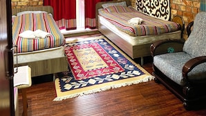 A cozy room with a bed, a chair, a patterned rug, and a stone wall. - Touristic Complex Chychkan (Bala-Chychkan)
