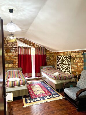 A cozy room with a bed, a chair, a patterned rug, and a stone wall. - Touristic Complex Chychkan (Bala-Chychkan)