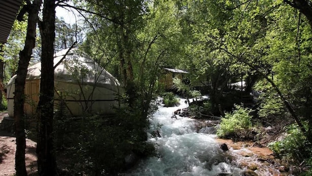 A river flowing through a forested area with a building partially visible on the left. - Touristic Complex Chychkan (Bala-Chychkan)