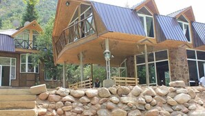 A unique, modern building with a sloped roof and large windows, surrounded by a stone wall and steps. - Touristic Complex Chychkan (Bala-Chychkan)
