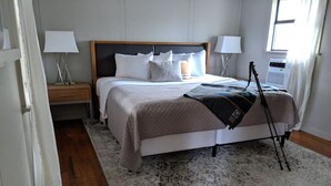 Une chambre à coucher avec un lit, des tables de chevet, des lampes et une fenêtre.