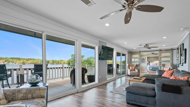 A spacious living area with a large sliding glass door leading to a deck, a ceiling fan, and a television mounted on the wall. - The VIEW @ Farr Shores! (Hot Springs)