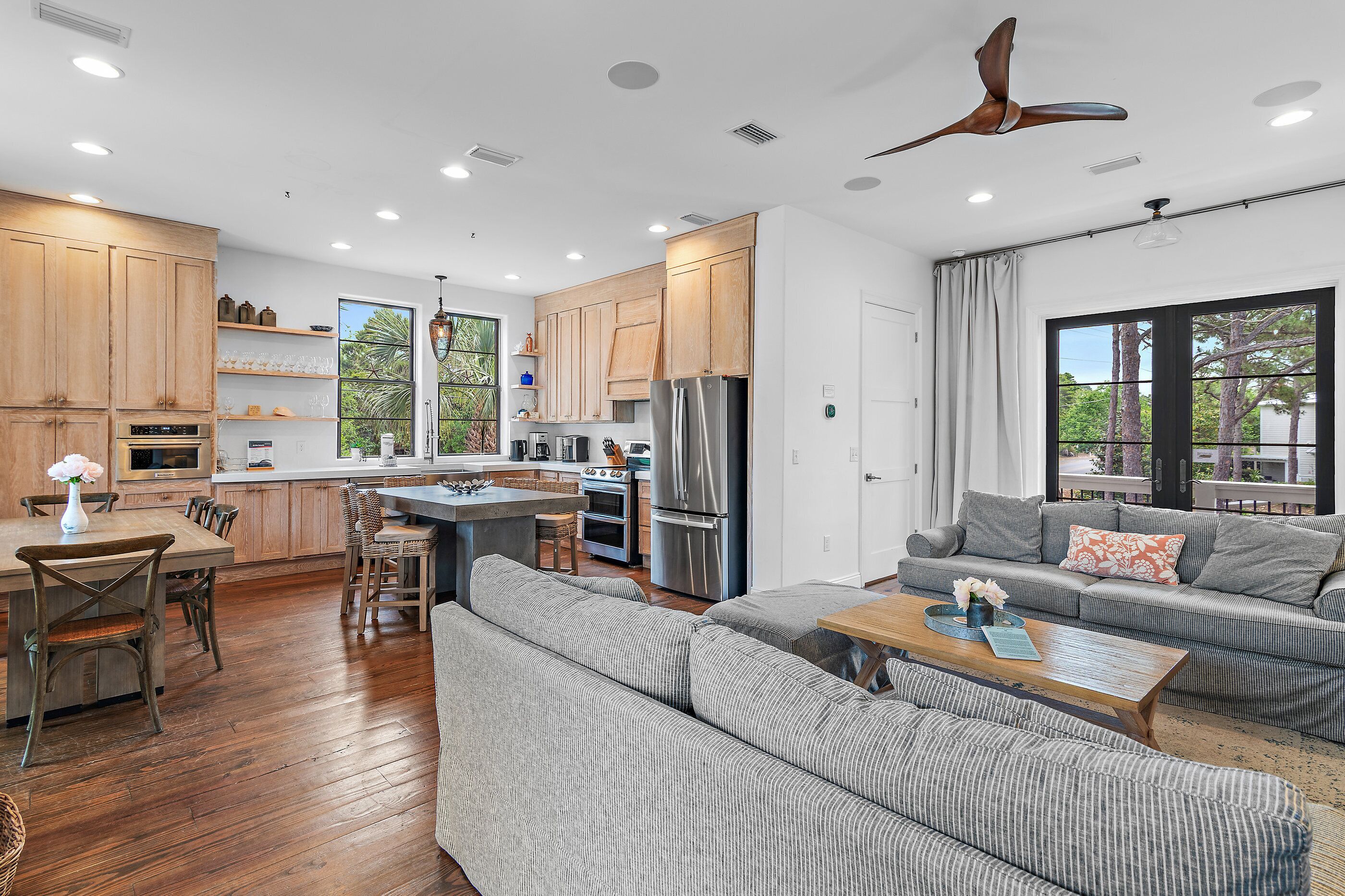 A modern kitchen with wooden cabinets, a central island, and a dining area with a wooden table and chairs.