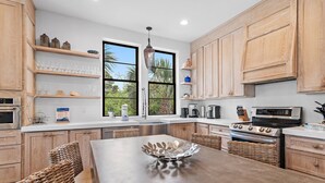 A modern kitchen with wooden cabinets, a central island, and a large window.