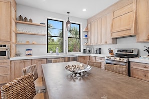 A modern kitchen with wooden cabinets, a central island, and a large window.