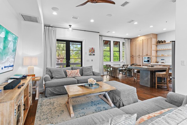 A modern living room with a sofa, coffee table, and a kitchen area with wooden cabinets and a bar.