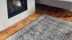 Une chambre avec un mur en briques, une cheminée, un lit et un téléviseur fixé au-dessus de la cheminée.