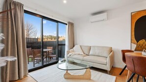 Un salon moderne avec une table basse en verre, un canapé et un coin repas avec des chaises.