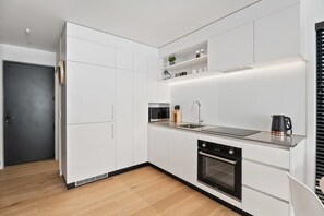 A modern kitchen with white cabinetry, a built-in oven, and a stainless steel sink.