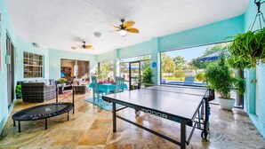 A spacious indoor area with a ping pong table, a trampoline, and ceiling fans. - Private Villa | Heated Pool + Hot Tub + Sleeps 20 (Port St. Lucie)