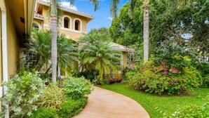 A curved pathway leading to a building with a yellow facade and arched windows. - Private Villa | Heated Pool + Hot Tub + Sleeps 20 (Port St. Lucie)