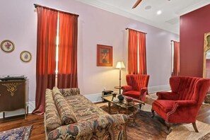 A room with a sofa, armchairs, a table, and curtains.