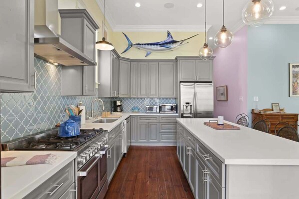 A modern kitchen with grey cabinets, a central island, and a blue fish decoration on the wall.