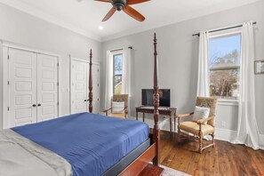 A bedroom with a four-poster bed, a television, a chair, and a desk.