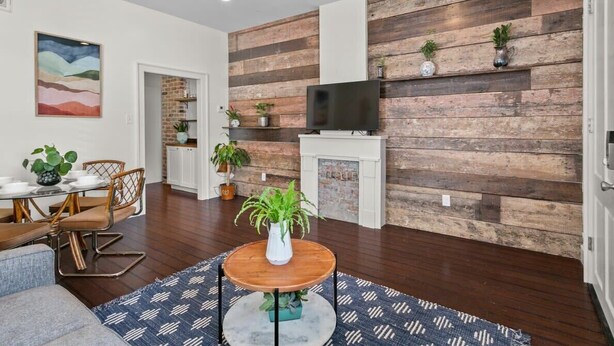 Un salon moderne avec un mur d’accent en bois, une cheminée et un coin repas comprenant une table et des chaises.