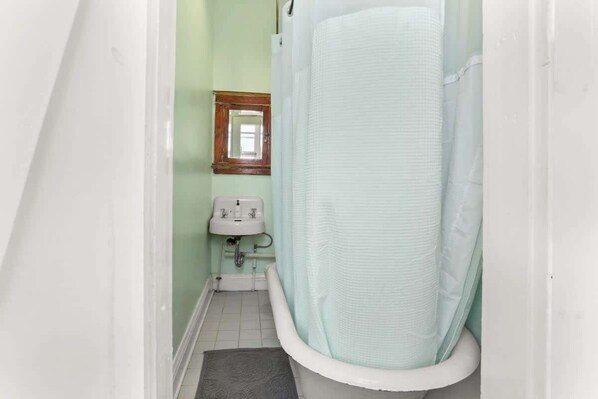 Un baño estrecho con bañera, lavabo y espejo.