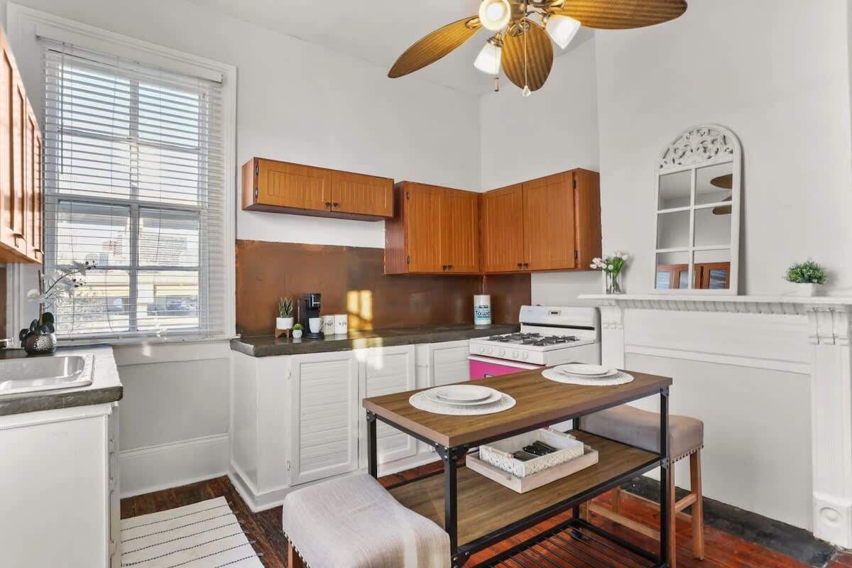 A compact kitchen with white cabinets, a wooden countertop, a gas stove, and a ceiling fan.