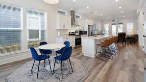A modern kitchen with white cabinets, a central island, and blue chairs.