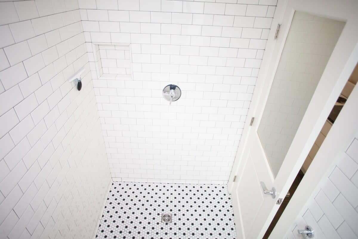 A small, white-tiled bathroom with a white floor and a white door.
