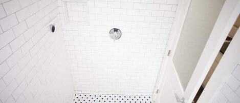 A small, white-tiled bathroom with a white floor and a white door.