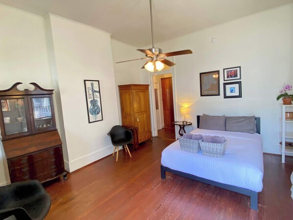 A bedroom with a bed, a ceiling fan, a dresser, a chair, and a map on the wall.