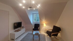 A modern living room with a TV, a coffee table, a chair, and a lamp.