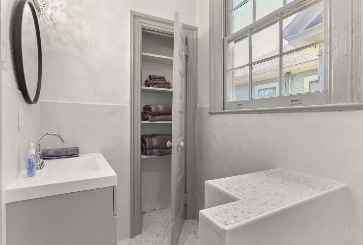 Un baño con lavamanos, espejo, espacio para toallas y ventana.