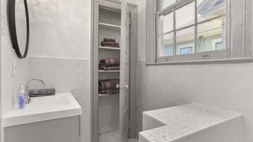 Un baño con lavamanos, espejo, espacio para toallas y ventana.