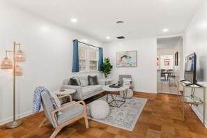 Una sala de estar moderna con un sofá, un sillón, una mesita de centro y una lámpara de pie.