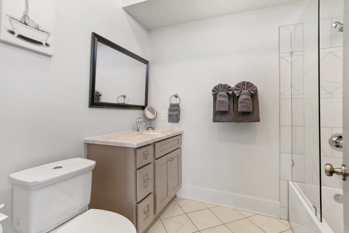 Een moderne badkamer met toilet, wastafel, spiegel en douche.