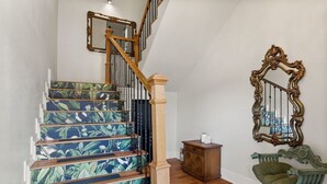 Una escalera con diseño floral, barandilla de madera y un mueble pequeño.
