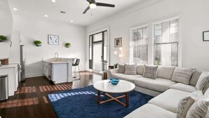 A modern living room with a sofa, coffee table, and a ceiling fan. - Modern 2BR | Garden District | Stunning Luxury (New Orleans)