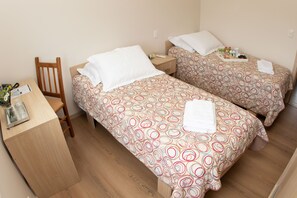 Un dormitorio con dos camas individuales, un escritorio de madera y una silla.