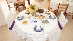 Una mesa redonda para comer cubierta con manteles blancos, platos con diseño azul y blanco, y cintas púrpuras en las sillas.