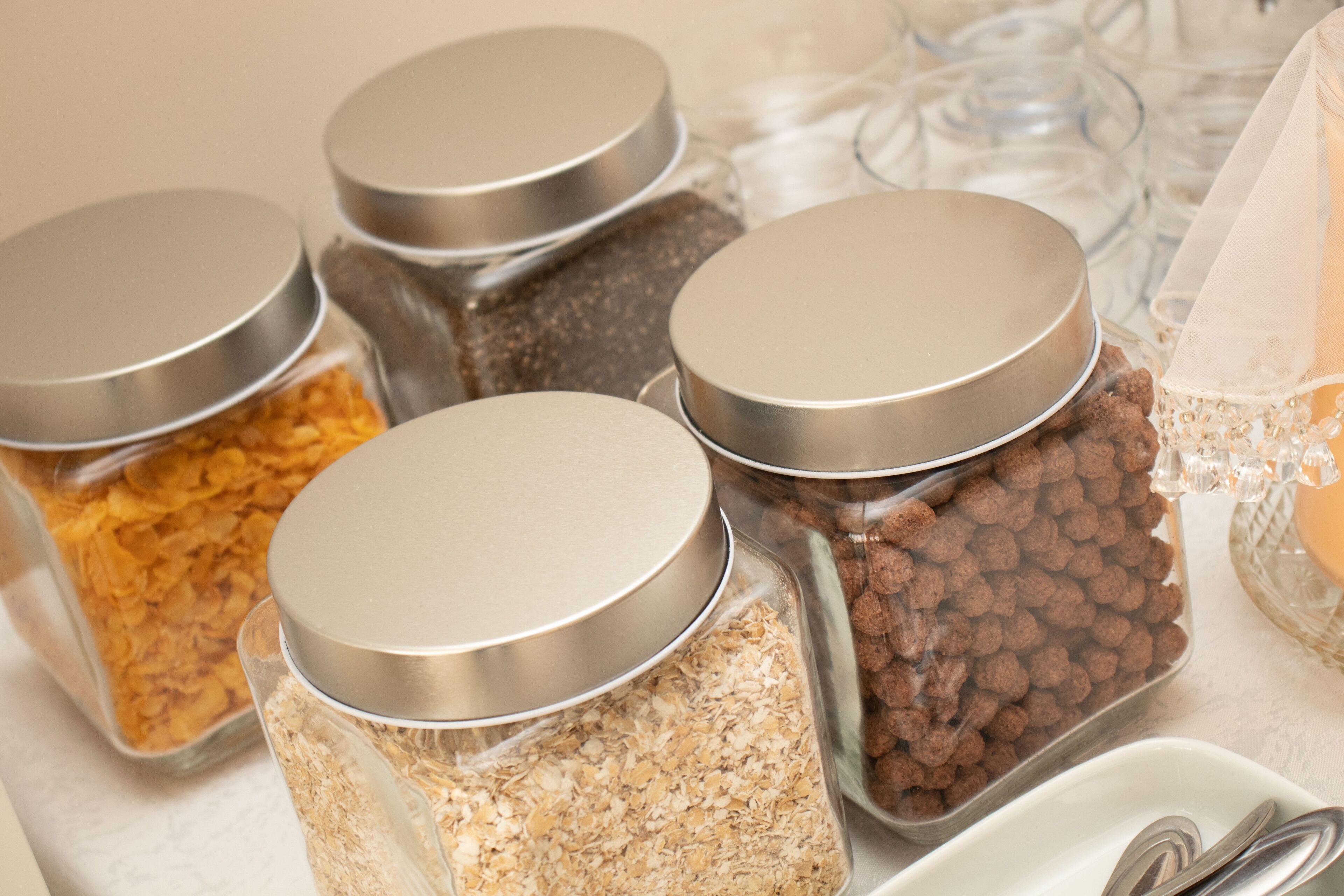 A variety of food items in containers with metal lids, including cereals and other snacks.