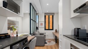 A compact kitchen with a washing machine, a dining area with a sofa, and a coffee machine. - Stunning Central Studio at The Carrington (Cape Town)