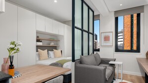 A modern, compact living space with a sofa, a small table, and a bed. - Stunning Central Studio at The Carrington (Cape Town)