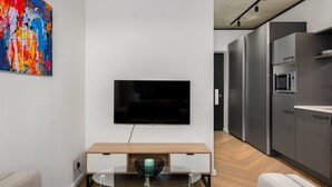 Ein modernes Wohnzimmer mit einem Flachbildfernseher an einer weißen Wand, einem Glastisch und einem Holztisch.