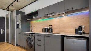 Eine moderne Küche mit grauen Schränken, einer Waschmaschine, einer Kaffeemaschine und einem Kühlschrank.