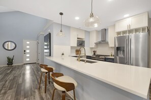 Una cucina moderna con una grande isola, elettrodomestici in acciaio inossidabile e sgabelli da bar in legno.
