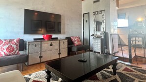 A living room with a sofa, a coffee table, a television, and a cabinet. - Incredible Gulf & Sunset Views From Balcony in Seaside + 2 Adult Bikes! (Santa Rosa Beach Fl)