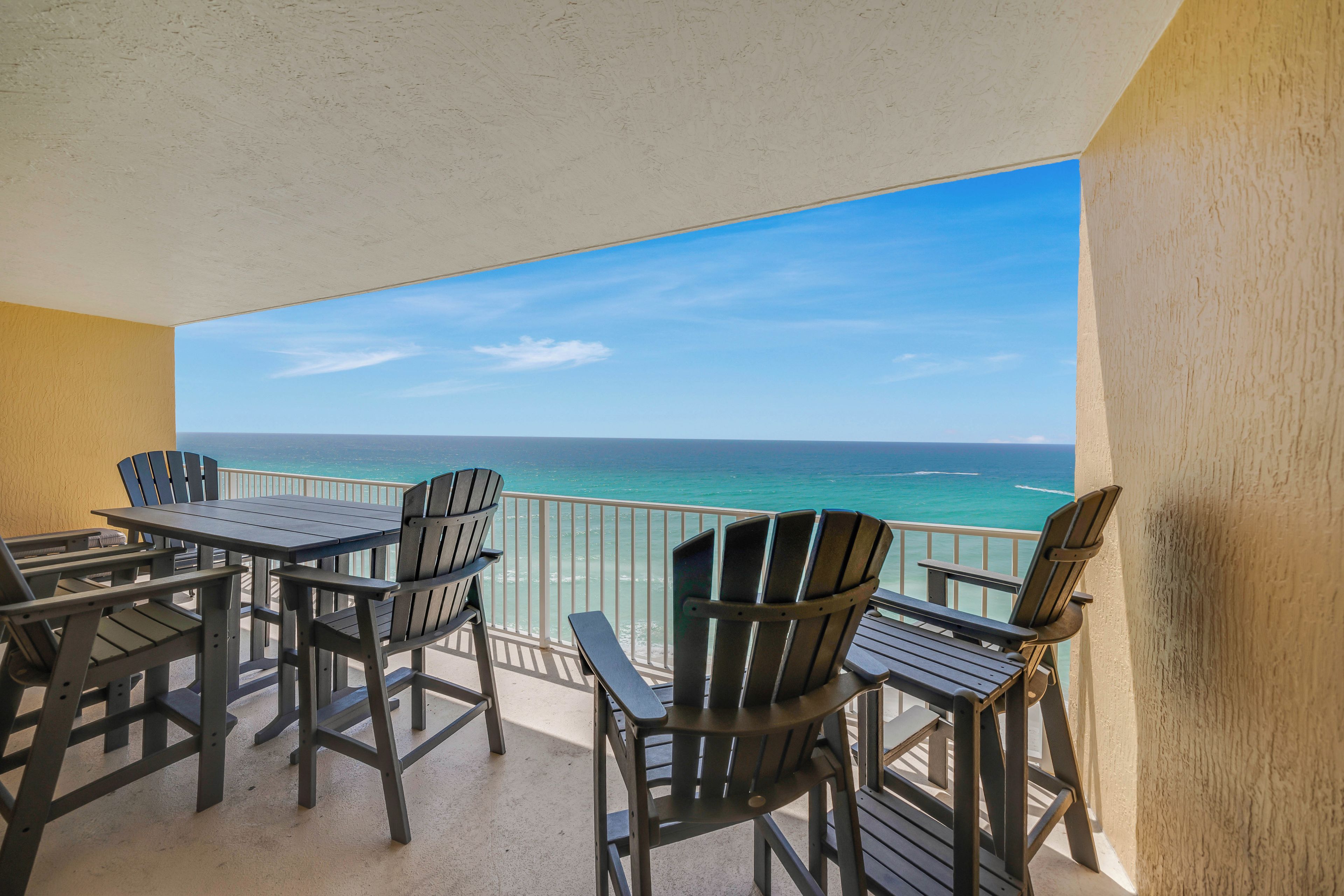 Un balcon avec vue sur l’océan, aménagé avec des chaises et une table.