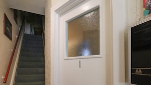 Uma porta branca com janela, escada e televisão presa na parede.