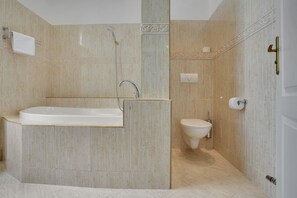 Deluxe tweepersoonskamer | Badkamer | Een bad, handdoeken, zeep, toiletpapier