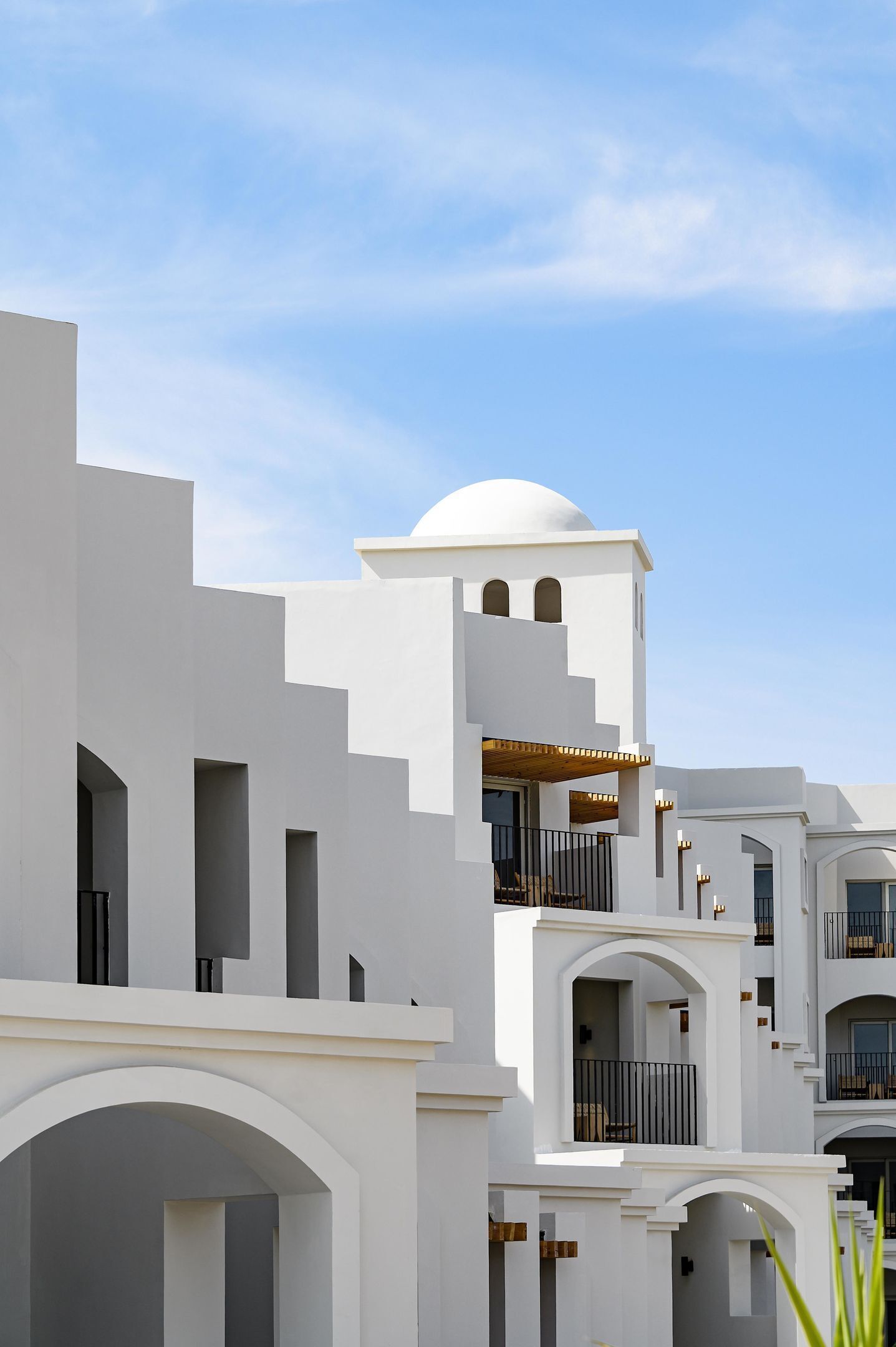 A modern white building with multiple balconies and a dome structure.